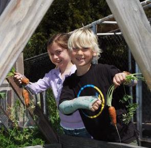 2 children holding up vegetables